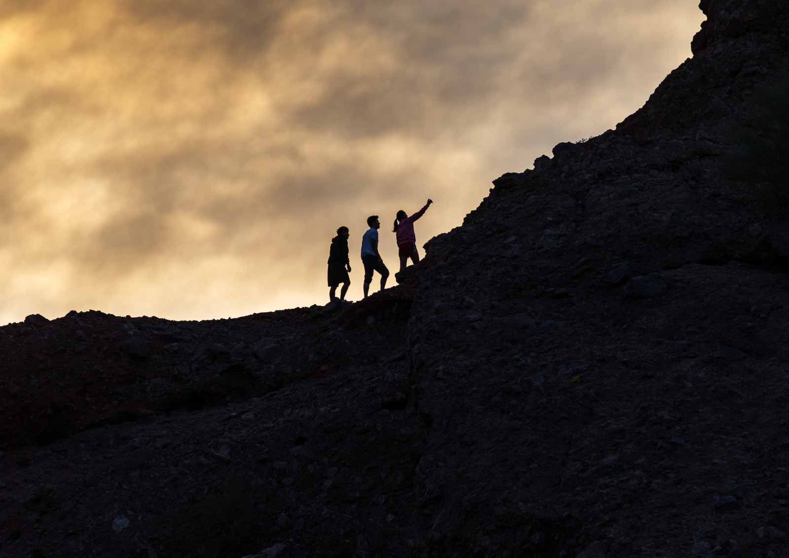 Three people climbing a hill