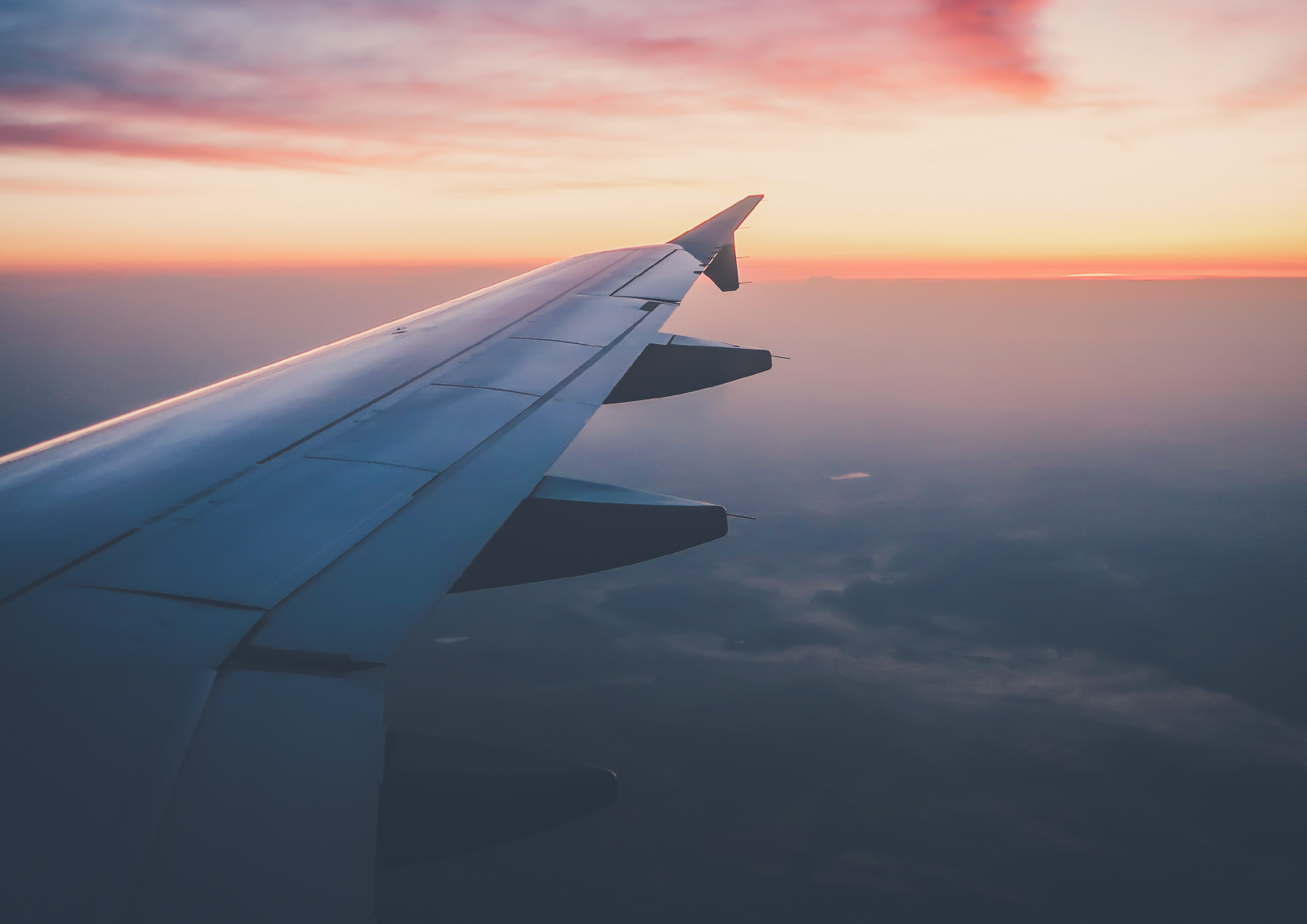 Photo of plane wing taken from inside plane in flight at sunset